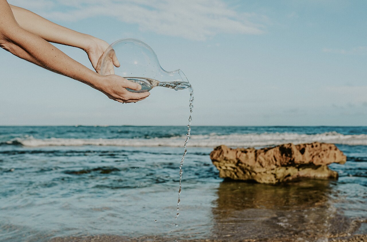 Water poured from the Kèrègbè glass carafe by the sea