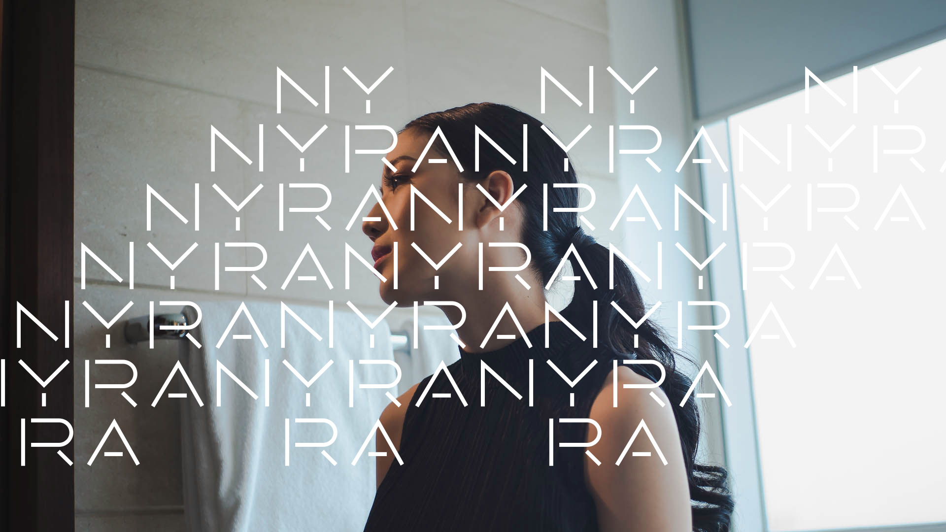 An Asian woman in black with long hair in a bathroom, looking out, with the word NYRA repeatedly laid out over the image in white to create a pattern